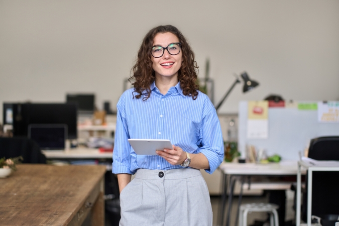 Young woman holding an Ipad and smiling in an office