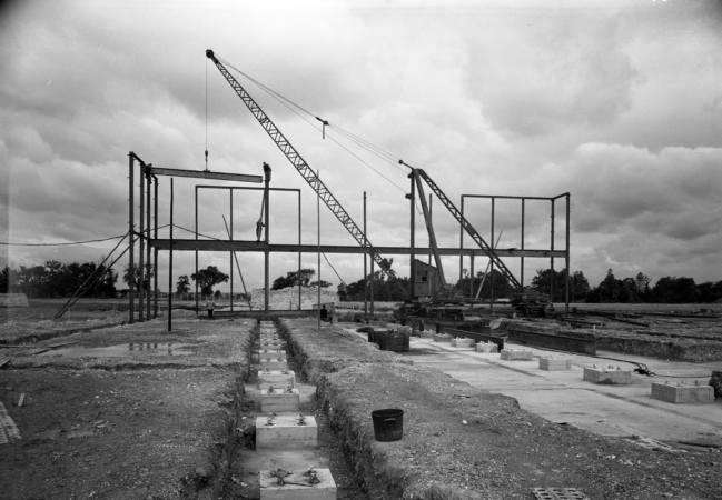 Black and white image of building construction showing metal frame and a crane