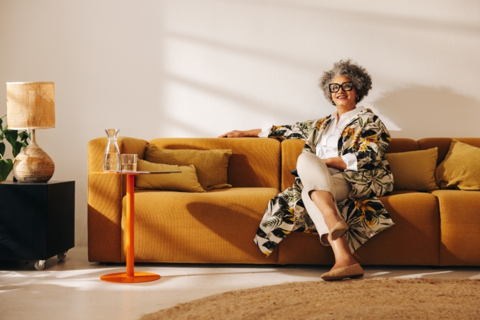 Experienced businesswoman smiling at the camera while sitting on a couch in an office lobby. Happy senior businesswoman working in a creative coworking office.
