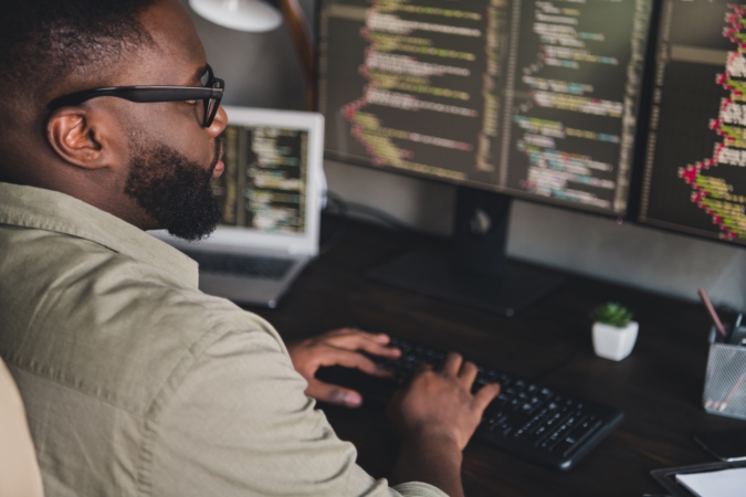 Profile side view of a focused, experienced, and skilled professional working intently on data editing at their workstation