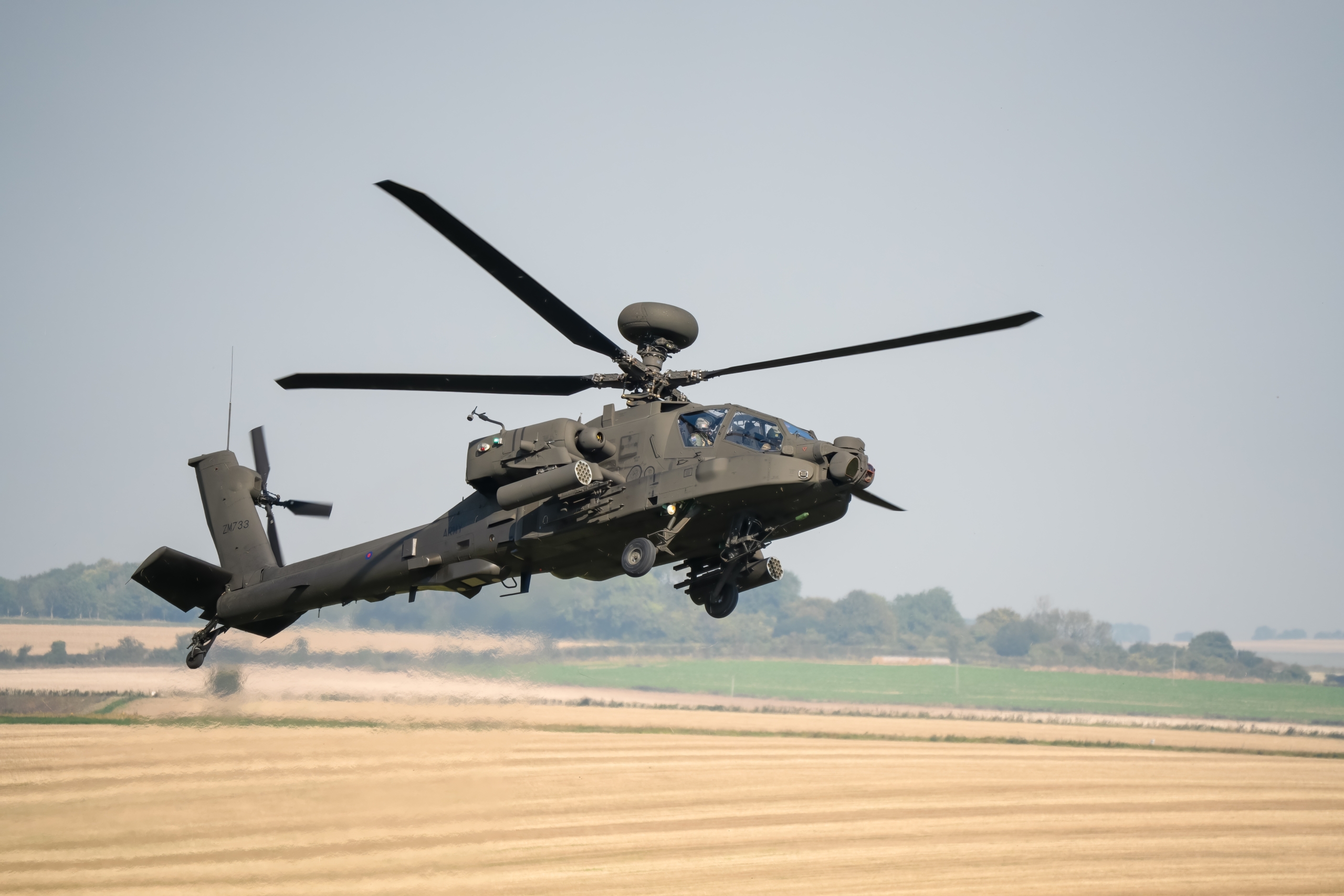 close-up right side view of a banking British army Boeing Apache Attack helicopter AH2 AH64E AH-64E ArmyAir in low level flight