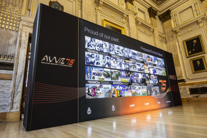A commemorative display in a grand room with marble columns and historic portraits, showcasing AWE's 75-year timeline of nuclear security technologies from the 1940s to the present, under the slogan 'Proud of our past. Prepared for the future.'